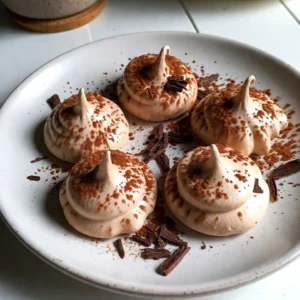 To make Mocha Meringue Cookies, you need a few key items: - 3 large egg whites - 1/4 teaspoon cream of tartar - 1 cup granulated sugar - 1 tablespoon instant coffee granules - 2 tablespoons unsweetened cocoa powder - 1 teaspoon vanilla extract - A pinch of salt These ingredients create a light and airy texture. The egg whites provide volume, while the sugar adds sweetness. The coffee and cocoa give a rich mocha flavor. You can elevate your cookies with these simple garnishes: - Chocolate shavings - Additional cocoa powder These add a nice touch. They enhance the look and make each bite more delightful. To prepare your Mocha Meringue Cookies, gather the following tools: - Electric mixer - Large mixing bowl - Rubber spatula - Piping bag with a large round or star tip - Baking sheet - Parchment paper Having the right tools makes the process easier. It helps you create beautiful cookies with ease. {{ingredient_image_2}} First, set your oven to 225&deg;F (110&deg;C). This low heat keeps the meringue cookies light. Next, take a baking sheet and line it with parchment paper. Make sure it lies flat and smooth. This helps the cookies not to stick. Grab a large mixing bowl and add three large egg whites. Use an electric mixer to whip them on medium speed. Beat until they start foaming and look frothy. When they are frothy, add 1/4 teaspoon of cream of tartar and a pinch of salt. Turn the mixer up to high speed. Keep beating until soft peaks form. The egg whites should look billowy and fluffy. Now, it&rsquo;s time to add flavor. Gradually mix in one cup of granulated sugar, adding about a tablespoon at a time. Keep beating until the mixture is shiny and stiff peaks form. This takes about 5 to 7 minutes. Next, use a rubber spatula to fold in one tablespoon of instant coffee granules and two tablespoons of cocoa powder. Don&rsquo;t forget the one teaspoon of vanilla extract! Be gentle when you fold these in. You want to keep the air in the egg whites for a light texture. To get the best texture, start with clean, dry tools. Any grease can ruin your egg whites. When you whip the egg whites, look for soft peaks first. This means they should gently hold their shape. Once you add the sugar, whip until you see stiff peaks. This step is key. The meringue should be glossy and firm, not runny. A good test is to turn the bowl upside down. If it stays put, you did it right! One common mistake is rushing the sugar. Add it slowly, about one tablespoon at a time. This helps the sugar dissolve well. Another mistake is over-mixing after adding the cocoa and coffee. Be gentle when folding in these ingredients. You want to keep the air in the meringue. Lastly, don&rsquo;t skip the cooling step in the oven. This helps prevent cracks and keeps your cookies light. When folding, use a rubber spatula. Start from the bottom and lift the mixture gently. This helps combine without losing air. Make sure to fold in the coffee and cocoa evenly. You want every bite to have that mocha flavor. If you see streaks, give it a few more gentle folds. Remember, the goal is to keep the mixture airy and fluffy, so be kind to your meringue! Pro Tips Use Room Temperature Egg Whites: For the best volume, let your egg whites sit at room temperature for about 30 minutes before whipping. This helps them whip up to a greater volume. Don't Rush the Sugar Addition: Adding sugar gradually is crucial. If you add it too quickly, the meringue may not achieve the desired glossy finish and stiff peaks. Monitor Oven Temperature: Proper baking temperature is key. If your oven runs hot, it could cause the meringues to crack. Use an oven thermometer for accuracy. Store in an Airtight Container: To keep your meringue cookies crisp, store them in an airtight container at room temperature. Avoid refrigerating, as moisture can make them chewy. {{image_4}} You can change the flavor of your mocha meringue cookies easily. For a minty twist, add a few drops of mint extract. This brings a fresh taste to each bite. If you love hazelnut, mix in hazelnut extract instead. You can also fold in finely ground hazelnuts for a crunchy texture. Both options pair well with coffee and chocolate. If you want to skip eggs, you have choices. Aquafaba, the liquid from canned chickpeas, works great here. Use 3 tablespoons of aquafaba instead of egg whites. Whip it like you would egg whites. This keeps the light and airy texture you love. Just add the same sugar and flavors, and bake as usual. Piping styles can change how your cookies look. Use a large round tip for simple mounds. This style gives a classic look. A star tip can create swirls that look fancy. You can even use a small round tip for tiny cookies. Just remember to space them out on the baking sheet. This keeps them from sticking together. Each style adds a unique touch to your dessert. To keep your mocha meringue cookies fresh, store them in an airtight container. Place a piece of parchment paper between layers to prevent sticking. Keep them in a cool, dry place away from moisture. Avoid the fridge, as humidity can ruin their texture. When stored properly, these cookies can last up to two weeks. After that, they may lose their crispness. Check for any signs of moisture or a change in texture. If they feel soft or sticky, it&rsquo;s best to toss them. You can freeze mocha meringue cookies for longer storage. First, let them cool completely. Then, place them in a single layer on a baking sheet. Freeze them for about an hour. Once frozen, transfer them to an airtight container or a freezer bag. They can last up to three months in the freezer. To enjoy, thaw them at room temperature for a few hours before serving. Chewy meringue cookies often come from too much humidity. High moisture can cause them to stay soft inside. Make sure you whip the egg whites well to form stiff peaks. This helps create a light, airy texture. Also, ensure your oven is at the correct low temperature. Baking them for too short a time can also lead to chewiness. You can use powdered sugar, but it may change the texture. Granulated sugar helps create a crisp outer shell. Powdered sugar will make the meringue softer and less crunchy. If you want to try it, use the same amount. Just remember, the meringue might not hold its shape as well. To check if your cookies are done, look for a few key signs. They should feel dry to the touch and lift off the parchment easily. They should not be soft or sticky. Baking for 1.5 to 2 hours at 225&deg;F helps ensure they dry out completely. After baking, leave them in the oven with the door ajar for an hour. This helps them cool down without cracking. Mocha meringue cookies mix simple ingredients and clear steps. We covered the main components, how to prepare them, and key tips for success. Don't forget the fun variations to try. Get creative with flavors and piped designs. Store them properly, and they will stay fresh longer. With practice, you&rsquo;ll make these cookies perfect every time. Enjoy baking and sharing these tasty treats!