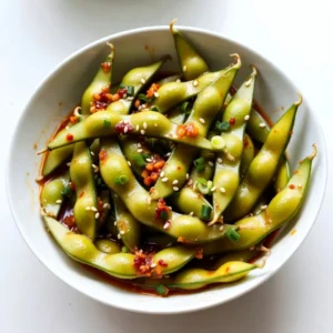 - 2 cups edamame in pods (fresh or frozen) - 3 tablespoons high-quality olive oil - 4 cloves garlic, finely minced - 1-2 tablespoons chili paste (adjust based on desired heat level) - 1 tablespoon soy sauce - 1 teaspoon toasted sesame oil - 1/2 teaspoon sea salt - 1 tablespoon sesame seeds - Chopped green onions for garnish (optional) I love using fresh or frozen edamame for this snack. The bright green pods add color and flavor to any meal. Olive oil is my go-to for cooking. It gives a nice richness that makes everything taste great. Garlic brings a strong, warm taste that pairs well with edamame. I use four cloves, but you can add more if you love garlic. Chili paste adds heat. You can adjust how much you use based on how spicy you want it. Soy sauce gives a salty, umami flavor. Toasted sesame oil adds a nutty touch. Sprinkle sea salt for extra seasoning. Finally, sesame seeds and green onions make the dish look nice. These ingredients come together to make spicy garlic edamame a tasty and quick snack. {{ingredient_image_2}} Cooking fresh edamame: To cook fresh edamame, bring a pot of salted water to a boil. Add the edamame pods. Cook them for about 5-6 minutes. They should feel tender but remain bright green. After cooking, drain them and set aside. Cooking frozen edamame: If you use frozen edamame, just follow the package instructions. Usually, you’ll boil or steam them until tender. Once they are cooked, drain and set aside. Heating the olive oil: In a large skillet, pour in 3 tablespoons of olive oil. Set the heat to medium. Wait until the oil shimmers, which shows it’s ready for the next step. Sautéing the garlic: Add 4 cloves of finely minced garlic to the hot oil. Stir frequently for 1-2 minutes. You want the garlic to be fragrant and lightly golden. Be careful not to burn it, as burnt garlic can ruin the flavor. Adding chili paste and soy sauce: Once the garlic is aromatic, it’s time to add flavor. Stir in 1-2 tablespoons of chili paste and 1 tablespoon of soy sauce. Mix well to create a spicy garlic sauce. Tossing in the edamame: Now, add the cooked edamame pods to the skillet. Toss them in the sauce. Make sure every pod is well-coated. Stir-fry for 3-4 minutes. This allows the flavors to blend perfectly. Adding sesame oil and sea salt: Drizzle 1 teaspoon of toasted sesame oil over the edamame. Sprinkle with 1/2 teaspoon of sea salt. Give everything a final toss to mix. Garnishing with sesame seeds and green onions: Remove the skillet from heat. Transfer the edamame to a serving bowl. If you want, sprinkle 1 tablespoon of sesame seeds and some chopped green onions on top. This adds a nice touch and crunch. - Choosing the right olive oil: Use a high-quality olive oil. It adds great flavor. Look for extra virgin oil. It has the best taste and health benefits. A good brand makes a big difference. - Not burning the garlic: Keep an eye on the garlic. It cooks fast and can burn easily. Stir it often and watch for a light golden color. Burned garlic tastes bitter, and we don't want that. - Adjusting heat level with chili paste: Start with one tablespoon of chili paste. Taste it, then add more if you want more heat. You control the spice. This recipe can be mild or fiery based on your choice. - Additional toppings for extra flavor: Consider adding toppings like sesame seeds or green onions. They add crunch and color. You can also try crushed red pepper or a squeeze of lime for a fresh kick. These small touches elevate your dish. Pro Tips Fresh vs. Frozen Edamame: If possible, opt for fresh edamame as it tends to have a better texture and flavor. Frozen edamame works as a great time-saver, just ensure it is cooked properly. Adjusting Spice Levels: Start with 1 tablespoon of chili paste if you're unsure about the heat. You can always add more later, but it's difficult to reduce spice once it's in the dish. Perfect Garlic Sauté: Keep an eye on the garlic while sautéing. It should be fragrant and lightly golden, but not burnt, as burnt garlic will impart a bitter taste to your dish. Serving Suggestions: Consider pairing your edamame with a refreshing drink like iced tea or a light beer to balance the spiciness and enhance your snacking experience. {{image_4}} You can adjust the spiciness of your edamame to fit your taste. For a mild version, use less chili paste. Start with just one tablespoon and taste. This way, you keep the garlic flavor strong without too much heat. If you love spicy food, try an extra spicy version. Add two tablespoons of chili paste. You can even mix in some red pepper flakes for a kick. Just be careful, as too much heat can overpower the dish. You can easily swap some ingredients for different flavors. For a healthier option, use avocado oil instead of olive oil. It has a mild taste and is rich in good fats. If you want a vegetarian option, use tamari instead of soy sauce. Tamari is gluten-free and has a rich flavor. It works well in this recipe, keeping the essence intact. Experimenting with these variations can help you find your perfect spicy garlic edamame! To keep your spicy garlic edamame fresh, store it right. First, let it cool to room temperature. Place the edamame in an airtight container. This helps lock in moisture and flavor. You can keep it in the fridge for up to three days. If you want to keep it longer, consider freezing it. To freeze, spread the cooled edamame in a single layer on a baking sheet. Once frozen, transfer it to a freezer-safe bag. This way, you can enjoy this tasty snack later. When you are ready to enjoy your edamame again, reheat it carefully. The microwave works well for this. Place the edamame in a microwave-safe bowl. Add a splash of water to keep it moist. Cover the bowl with a microwave-safe lid or wrap. Heat in short bursts, about 30 seconds at a time. Stir and check the edamame until warm. You can also reheat it in a skillet. Just add a little olive oil over medium heat. Stir gently until warmed through, and it will taste great again. Edamame are young soybeans. They grow in pods and are popular in many dishes. They are often served as a snack or appetizer. Edamame is packed with protein, fiber, and vitamins. This makes them a great healthy choice. One cup of edamame provides about 17 grams of protein. They also have antioxidants and help with heart health. Yes, you can use other legumes if needed. Some good substitutes are green peas, black beans, or chickpeas. Each offers a different taste and texture. Green peas are sweet and tender. Black beans give a rich flavor. Chickpeas provide a nice bite. You can adapt your sauce to match these legumes. Cooking time varies based on the type of edamame. Fresh edamame takes about 5-6 minutes in boiling water. Frozen edamame usually needs around 4-5 minutes. Always check the package for specific instructions. Both options should be tender but still bright green. This helps keep their flavor and nutrients. In this blog post, I shared a simple recipe for making a tasty edamame dish. We discussed ingredients, cooking steps, and helpful tips to enhance flavor. Remember to adjust the chili paste for your preferred spice level. You can also try substitutions if needed. Whether for a snack or a side, this recipe is quick and easy. Enjoy making your edamame dish, and don’t hesitate to experiment for your perfect flavor!
