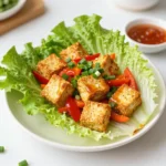 - 1 block (14 oz) firm tofu, pressed and cut into cubes - 1/4 cup sweet chili sauce - 1 red bell pepper, diced into small pieces - 1 medium carrot, grated - 3 green onions, finely chopped - 2 tablespoons cornstarch - 2 tablespoons vegetable oil - 1 tablespoon soy sauce - 1 tablespoon fresh lime juice - Salt and pepper to taste - Chopped green onions - Fresh cilantro - Lettuce leaves (butter or romaine) These ingredients come together to create a fresh and tasty meal. Firm tofu provides a nice base, while sweet chili sauce adds a sweet and spicy kick. Fresh vegetables keep the dish bright and crunchy. The seasoning ingredients, like soy sauce and lime juice, enhance the flavors. For garnishes, chopped green onions and cilantro bring freshness. Lettuce leaves are perfect for wrapping everything up, making each bite fun and easy to eat! {{ingredient_image_2}} - First, press the firm tofu for 15 minutes. This step removes extra moisture. - After pressing, cut the tofu into small cubes. This helps cook it evenly. - Next, toss the cubed tofu in cornstarch. Ensure each piece is coated well. This creates a nice crispy texture. - Heat vegetable oil in a large skillet over medium-high heat. - When the oil is hot, add the cornstarch-coated tofu to the skillet. - Fry the tofu, turning occasionally. Cook until golden and crispy for about 8 to 10 minutes. - Once the tofu is crispy, add the diced red bell pepper and grated carrot. - Sauté this mixture for 3 to 4 minutes. You want the veggies tender but vibrant. - Now, pour in the sweet chili sauce, soy sauce, and fresh lime juice. - Stir to coat everything well and let it simmer for 2 to 3 minutes. This helps the flavors blend. - Finally, taste the mixture and adjust with salt and pepper as needed. To get crispy tofu, pressing is key. Press the tofu for at least 15 minutes. This removes excess moisture and helps it crisp up. Always use firm tofu for the best texture. After pressing, cut it into small cubes. This size cooks evenly and gets crispy all around. For frying, coat the tofu in cornstarch. This helps create a crunchy layer when you fry it. Heat vegetable oil in a skillet until it's hot. Add the tofu cubes, and let them fry without moving too much. Cook them for about 8-10 minutes. Turn them occasionally until they are golden on all sides. To boost the flavor, think about adding spices. You can use garlic powder, ginger, or even a bit of cayenne for heat. These spices work well with the sweet chili sauce. Speaking of sauce, try making your own sweet chili sauce. It’s simple to make and adds a fresh taste. Homemade sauce allows you to control the sweetness and spice level. Mix sugar, vinegar, and chili flakes to create your own blend. This can enhance the dish and make it even more special. When serving, presentation matters. Use a large platter for the lettuce wraps. Arrange the wraps neatly to show off the colors. Drizzle some extra sweet chili sauce over the wraps for a beautiful finish. You can also add sprigs of cilantro for a pop of green. For side dishes, think light. A simple cucumber salad pairs well. It adds a refreshing crunch that complements the wraps. You could also serve it with steamed rice or quinoa for a more filling meal. Pro Tips Press Tofu Properly: Ensure you press the tofu for at least 15 minutes to remove excess moisture. This step is crucial for achieving a crispy texture when cooked. Coat Evenly: When tossing the tofu with cornstarch, make sure each piece is evenly coated. This will enhance the crispiness and help the sauce adhere better. Adjust Flavor to Preference: Always taste the tofu mixture before serving. Adjust the seasoning with salt and pepper to your liking for a perfectly balanced flavor. Creative Garnishing: For an added touch, consider garnishing with sliced chili peppers or sesame seeds along with cilantro for extra flavor and visual appeal. {{image_4}} You can switch up the tofu with other plant-based proteins. Try chickpeas or lentils for a hearty option. You can also use mushrooms or tempeh. They add unique textures and flavors. Sautéed shiitake mushrooms work well for a meaty bite. Tempeh brings a nutty taste and a firm texture. Each choice offers a different twist to the wraps. Want to change the taste? Consider using different sauces. Hoisin or peanut sauce can add a new depth of flavor. You can also add nuts or seeds for a crunchy bite. Chopped peanuts or sesame seeds work great in these wraps. They not only add texture but also enhance the taste. If you need gluten-free options, replace soy sauce with tamari. This keeps the dish tasty without gluten. For those on low-carb diets, use leafy greens like collard greens instead of lettuce. They hold up well and give a satisfying crunch. Adjusting these elements helps you fit the wraps into any diet. Store your sweet chili tofu lettuce wraps in an airtight container. This keeps them fresh. Place them in the fridge right away. They stay good for about 3 days. If you wait too long, the lettuce gets soggy. To reheat your tofu wraps, take out the filling and leave the lettuce. Use a skillet for best results. Heat the filling over medium heat. Stir it often to warm evenly. Avoid the microwave. It can make tofu mushy and lettuce limp. Yes, you can freeze leftovers! But, only the tofu filling, not the lettuce. To freeze, place the tofu mixture in a freezer bag. Remove extra air to avoid freezer burn. When ready to eat, thaw it overnight in the fridge. Reheat in a skillet when you’re ready to enjoy! To get crispy tofu, start by pressing it. This removes extra water. Press for at least 15 minutes. After pressing, cut the tofu into cubes. Next, coat each cube in cornstarch. This helps create that nice crunch when you fry it. Heat vegetable oil in a skillet over medium-high heat. Add the coated tofu and fry until golden brown, about 8-10 minutes. Flip the tofu often for even cooking. Yes, you can swap sweet chili sauce with other sauces. Try using hoisin sauce for a sweet touch. You can also mix soy sauce with honey for a similar flavor. If you want less sweetness, use sriracha for some heat. Just keep in mind that the taste will change with each swap. For wraps, I suggest using butter or romaine lettuce. Butter lettuce is soft and easy to fold. It adds a nice crunch and looks great on a plate. Romaine lettuce has a sturdy structure, which holds the filling well. Both types keep your wraps fresh and tasty. Choose the one you like best! This article covered tasty tofu wraps, from key ingredients to storage tips. You learned about essential items like firm tofu, sweet chili sauce, and fresh veggies. I shared step-by-step instructions for preparing and cooking the tofu, ensuring it stays crispy. We explored flavor enhancements and variations for different diets. In summary, these wraps are easy to customize, fun to make, and great for any meal. Enjoy experimenting with flavors and techniques. Your tofu journey can be simple and delicious!