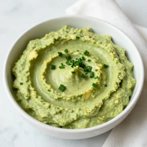 - 2 ripe avocados, halved and pitted - 1 cup sour cream - 1/2 cup mayonnaise - 1/4 cup buttermilk - 1 tablespoon ranch seasoning mix - 1 tablespoon fresh lemon juice - 1 clove garlic, finely minced - Salt and freshly ground pepper - Fresh herbs (chives, parsley) for garnish Gathering the right ingredients is key to making this creamy avocado ranch dip. Start with two ripe avocados. They should feel soft but not too mushy. Next, grab a cup of sour cream. This gives the dip a nice creaminess. You will also need half a cup of mayonnaise. It adds richness that balances the flavors well. Next is buttermilk, a quarter cup for some tanginess. One tablespoon of ranch seasoning mix brings all those good flavors together. Fresh lemon juice is a must, so grab one tablespoon for brightness. Add one clove of finely minced garlic for depth of flavor. Don't forget salt and freshly ground pepper to taste. Finally, fresh herbs like chives and parsley will add a lovely touch on top. Make sure you have everything ready before you start. Each ingredient plays an important role in creating a delicious dip that's perfect for any snack time! {{ingredient_image_2}} Start by cutting the avocados in half. Carefully remove the pits using a spoon. Scoop the green flesh into a mixing bowl. Ripe avocados are key for a creamy dip. In the bowl with the avocado, add the sour cream, mayonnaise, and buttermilk. Each adds a rich, creamy layer. Next, sprinkle in the ranch seasoning mix. Then, squeeze in the fresh lemon juice for a bright taste. Finally, add the finely minced garlic. Use a fork or an immersion blender to mash the mixture together. Blend until smooth and creamy. If you like a chunkier dip, stop blending sooner. The texture can be just how you like it. Once blended, taste your dip. Add salt and freshly cracked pepper to enhance the flavors. Adjust the seasoning as needed. This step is crucial for a balanced dip. Gently fold in some chopped fresh herbs like chives or parsley. This adds a fresh aroma and flavor. Carefully transfer your creamy dip to a serving bowl. Sprinkle extra chopped herbs on top for a nice garnish. Serve with fresh veggies, tortilla chips, or crackers for a colorful spread. Choose ripe avocados for the best dip. Look for avocados that feel slightly soft when you press them. They should not be too mushy or hard. A ripe avocado will have a dark green color. You can also check the stem; if it pops off easily and is green underneath, the avocado is ready. For a creamy dip, mash the avocados until smooth. You can use a fork or an immersion blender. If you like it chunkier, leave some small pieces. The sour cream and buttermilk help make it creamy. Adjust the amount of buttermilk for a thinner or thicker texture. Store any leftover dip in an airtight container. Press plastic wrap directly onto the dip's surface to keep it fresh. This helps prevent browning. Use the dip within two days for the best flavor. You can also mix in a little lemon juice to help keep it green longer. Pro Tips Use ripe avocados: Ensure your avocados are perfectly ripe for a creamy texture. They should yield slightly to gentle pressure when squeezed. Customize the herbs: Feel free to mix and match your favorite fresh herbs, like dill or cilantro, to create a unique flavor profile. Adjust the thickness: If you prefer a thinner dip, gradually add more buttermilk until you reach your desired consistency. Make it ahead: This dip can be made a day ahead and stored in the fridge. Just give it a good stir before serving to refresh its texture. {{image_4}} You can easily change the flavor of your creamy avocado ranch dip. One simple way is to add some diced jalape&ntilde;os. They give a nice kick and a fresh taste. You might also try adding a teaspoon of smoked paprika. This adds a deep, smoky flavor that pairs well with the creaminess of the dip. For a bit of sweetness, mix in some chopped roasted red peppers. They will brighten the dish, making it even more tasty. If you want a vegan version, you can swap out the dairy. Use coconut yogurt instead of sour cream. It adds creaminess without the dairy. For the mayonnaise, you can use vegan mayo. It keeps the richness while staying plant-based. Buttermilk can be replaced with almond milk mixed with a splash of vinegar. This will give you that tangy flavor. With these swaps, you still get a creamy dip that everyone can enjoy. Feel free to explore other flavors. For a zesty twist, add lime juice instead of lemon juice. This gives a fresh and bright taste. You can also try adding fresh herbs like cilantro or dill. Each herb brings its own unique flavor. If you want something savory, add a dash of Worcestershire sauce. It will deepen the flavor profile. Experimenting with these options can lead to new and exciting dips! To keep your creamy avocado ranch dip fresh, store it in an airtight container. The dip will stay tasty for up to three days in the fridge. If you notice browning on top, just stir it in. The dip will still taste good. Always seal it tight to prevent air from getting in. This helps keep the flavors strong. You can freeze this dip, but the texture may change. If you want to freeze it, use a freezer-safe container. Leave some space at the top for expansion. The dip can last up to two months in the freezer. When you&rsquo;re ready to eat it, thaw it in the fridge overnight. Stir well before serving to bring back its creamy texture. The creamy avocado ranch dip tastes best fresh, but it can last. In the fridge, expect it to stay good for about three days. If frozen, use it within two months for the best flavor. Always check for any off smells or changes in color before using. Freshness is key to enjoying this dip! To make creamy avocado ranch dip, start by cutting two ripe avocados in half. Remove the pits and scoop the green flesh into a bowl. Next, add one cup of sour cream and half a cup of mayonnaise. Then, pour in a quarter cup of buttermilk for tang. Add one tablespoon of ranch seasoning mix, one tablespoon of fresh lemon juice, and one minced garlic clove. Mash or blend the mix until smooth. If you like it chunkier, blend less. Finally, season with salt and pepper, then fold in some chopped fresh herbs. Yes, you can prepare this dip in advance. Make it up to two days before you plan to serve it. Just keep it in an airtight container in the fridge. The flavors will mix and get even better. Before serving, give it a good stir and taste for seasoning. This dip pairs well with many snacks. You can serve it with fresh vegetables like carrots, cucumbers, and bell peppers. Tortilla chips and crackers are also great choices. You could even spread it on a sandwich for an extra kick of flavor. Get creative and enjoy! This dip can fit into many diets. It contains dairy, so it may not suit those who are lactose intolerant or vegan. However, you can easily modify it by using dairy-free sour cream or yogurt. Check the ranch seasoning mix to ensure it aligns with any dietary needs. To add some heat, mix in spicy ingredients. Try adding diced jalape&ntilde;os or a few dashes of hot sauce. You could also sprinkle in cayenne pepper or chili powder to taste. Start with a little, then adjust until you reach your preferred spice level. This blog post covered how to make a creamy avocado ranch dip. I shared the ingredients you need and clear, step-by-step instructions. You learned how to prepare avocados, mix the ingredients, and blend for the right texture. I also highlighted tips for selecting avocados and safe storage methods. In the end, this dip is not just tasty but also versatile. Enjoy it as a snack or at your next gathering. You can easily customize it to fit your tastes. Happy dipping!