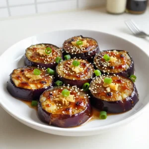 To make Miso Ginger Glazed Eggplant, you need: - 2 medium eggplants, sliced into 1-inch thick rounds - 3 tablespoons white or yellow miso paste - 2 tablespoons fresh ginger, grated - 2 tablespoons honey or maple syrup - 2 tablespoons soy sauce (or tamari for a gluten-free option) - 1 tablespoon sesame oil - 1 tablespoon rice vinegar - 2 cloves garlic, minced - 1 tablespoon sesame seeds (for garnishing) - Chopped green onions (for garnishing) Choose eggplants that are firm and smooth. Look for shiny skin without any blemishes or wrinkles. A good eggplant feels heavy for its size. Avoid any that seem soft or have dark spots. Smaller eggplants are often sweeter and less bitter. Always pick ones with bright green caps, which means they are fresh. If you can't find miso paste, try tahini or almond butter for creaminess. For soy sauce, coconut aminos work well as a gluten-free option. You can also mix in a bit of vinegar for tang. Adjust the flavors to your liking, but keep it simple. Cooking should be fun, and you can always experiment! {{ingredient_image_2}} First, preheat your oven to 400&deg;F (200&deg;C). This temperature helps the eggplant cook evenly. While your oven heats, get a baking sheet and line it with parchment paper. This step prevents the eggplant from sticking. Next, take your eggplants and slice them into 1-inch thick rounds. Now, let&rsquo;s make the glaze. In a medium bowl, combine miso paste, grated ginger, honey or maple syrup, soy sauce, sesame oil, rice vinegar, and minced garlic. Whisk these together until smooth. This glaze adds great flavor to the eggplant. Using a basting brush, apply the glaze to both sides of each eggplant slice. Make sure they are well-coated. This step gives each piece a rich taste. Place the baking sheet with the coated eggplant in the preheated oven. Bake it for about 25-30 minutes. To ensure even cooking, flip the slices halfway through. This helps both sides get that nice caramelized look. For even more flavor, baste the eggplant with any leftover glaze during this time. Caramelization brings out the sweetness in the eggplant. To get it just right, watch the time carefully. The eggplant should be tender and have a golden-brown color. If you notice that it isn&rsquo;t caramelizing as you want, leave it in a bit longer. Once ready, take the eggplant out of the oven and let it cool for a few minutes. This cooling helps set the glaze. When serving, sprinkle sesame seeds and chopped green onions on top. These add a lovely crunch and color. Enjoy your delicious dish! To boost the flavor of your miso ginger glazed eggplant, add a splash of citrus. Lemon or lime juice brightens the dish. You can also mix in some chili paste for a spicy kick. This extra layer makes each bite more exciting. Consider using toasted sesame oil instead of regular sesame oil. It adds a nutty richness that stands out. One common mistake is not salting the eggplant before cooking. Salting draws out moisture and bitterness. It helps the eggplant fry better and taste sweeter. Another mistake is overcrowding the baking sheet. Give each slice space to breathe. This helps them caramelize and brown evenly. Lastly, avoid skipping the basting step. It keeps the glaze moist and flavorful. For a beautiful presentation, use a large, colorful platter. Arrange the eggplant in a fan shape or stack vertically. Top with sesame seeds for crunch and chopped green onions for color. A drizzle of extra sesame oil adds shine and flavor. Fresh herbs like cilantro or basil can brighten the plate. Keep the garnishes simple to let the eggplant shine. Pro Tips Use Firm Eggplants: Choose firm and smooth eggplants for the best texture and flavor. Overripe eggplants can be bitter and mushy. Experiment with Miso: Different types of miso (red, white, yellow) offer varying flavors. Try using red miso for a deeper umami taste. Don't Skip the Marinade: Let the eggplant marinate in the miso glaze for at least 30 minutes before baking for more intense flavor. Garnish Creatively: Consider adding crushed peanuts or chili flakes as additional garnishes for a delightful crunch and heat. {{image_4}} You can easily make this glaze vegan. Simply swap honey for maple syrup. This sweetener gives a nice taste while keeping it plant-based. Besides maple syrup, you can also use agave nectar. Both options work great and taste wonderful. While eggplant shines in this recipe, other veggies work too. Try zucchini, bell peppers, or even carrots. Slice them into thick pieces to mimic the eggplant. The glaze will add flavor to any vegetable you choose. Just remember to adjust the baking time based on the vegetable's thickness. You can play with flavors in the glaze. Add a pinch of chili flakes for heat. Or mix in fresh basil for a sweet twist. Using cilantro or mint adds a fresh touch. Experiment with these options to find your favorite flavor combo. Each change can make the dish feel new and exciting. To keep leftover miso ginger glazed eggplant fresh, store it in a sealed container. Make sure it cools down first. Place a piece of parchment paper between layers if stacking. This helps avoid sogginess. Store it in the fridge for up to three days. When reheating, use the oven for best results. Preheat your oven to 350&deg;F (175&deg;C). Place the eggplant slices on a baking sheet. Heat them for about 10 minutes. This method keeps the eggplant crispy. You can also use a microwave. Just heat for one minute, checking often to prevent drying. You can freeze baked eggplant, but it may lose texture. Let it cool completely. Place pieces in a single layer on a baking sheet. Freeze until solid, then transfer to a freezer bag. Remove as much air as possible. It can last up to three months. When ready to eat, thaw in the fridge overnight. Reheat in the oven for best results. Yes, you can use other types of miso paste. White miso is mild and sweet. Yellow miso has a slightly stronger flavor. Red miso is bold and salty. Each type brings a unique taste. Choose based on your preference. Miso ginger glazed eggplant lasts about 3 to 5 days in the fridge. Store it in an airtight container. This keeps it fresh and tasty. Reheat it in the oven or microwave before serving. Miso ginger glazed eggplant pairs well with rice or quinoa. It also complements stir-fried veggies and tofu. Add a side of steamed broccoli for color. A light salad can balance the flavors, too. Enjoy experimenting with different sides! Miso ginger glazed eggplant is easy to make and full of flavor. You learned about choosing the best eggplant and how to coat it for baking. We explored tips to avoid common mistakes and make your dish shine. You can even swap ingredients and try different veggies. Remember to store your leftovers properly to keep them tasty. Now, get ready to enjoy this delicious dish and impress your friends and family. Happy cooking!
