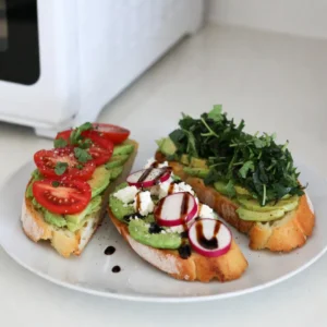 To make the Minute Avocado Toast Trio, you need a few key items. Here’s what you will need: - 2 ripe avocados - Juice of 1 small lemon - Salt and freshly cracked black pepper, to taste - 4 slices of whole grain bread - 1 small ripe tomato, thinly sliced - 1 radish, thinly sliced - 1 tablespoon crumbled feta cheese - 1 tablespoon balsamic glaze - Assorted fresh herbs (like cilantro, basil, or parsley) for garnish These ingredients create a tasty base for your avocado toasts. The ripe avocados bring creaminess, while the lemon juice adds brightness. You can add more flavors to your toasts if you wish. Here are some great options: - Red pepper flakes for heat - Sliced olives for a briny kick - A drizzle of olive oil for richness - Toasted seeds or nuts for crunch - A sprinkle of garlic powder for depth These add-ins can make your toast even more exciting and flavorful. Try mixing and matching to find your favorite combo. The bread choice can make or break your toast. Here are some great options: - Whole grain bread for a hearty base - Sourdough for a tangy twist - Multigrain for added texture - Gluten-free bread if you need it Toasting the right bread will give you that perfect crunch. Enjoy your delicious avocado toast with these simple yet effective choices! {{ingredient_image_2}} To start, grab two ripe avocados. Slice them in half and take out the pits. Use a spoon to scoop the creamy green flesh into a mixing bowl. Next, squeeze the juice from one small lemon into the bowl. This helps keep the avocado fresh and adds flavor. Add a pinch of salt and a few cracks of black pepper for taste. With a fork or potato masher, mix everything until smooth or chunky, depending on your preference. Now it's time to toast the bread. Use four slices of whole grain bread for a healthy option. You can use a toaster or a skillet. If using a skillet, heat it over medium heat. Toast each slice for about 2-3 minutes until golden brown and crispy. If you like, add a dash of olive oil to the skillet for extra flavor. Let’s assemble the toasts. For the first toast, spread a layer of the avocado mix on one slice. Top it with thin slices of tomato. Add a sprinkle of salt and a few fresh herbs for flavor. For the second toast, layer another slice with the avocado mix. Top this one with thin radish slices and crumbled feta cheese. Finish it with a drizzle of balsamic glaze for a sweet touch. Finally, take the last slice and spread a thick layer of avocado. Garnish it with a mix of fresh herbs. If you want, add more salt for taste. Arrange all three toasts on a serving platter. Drizzle some extra lemon juice and a hint of olive oil on top. Serve them right away for the best taste! To pick the best avocados, look for ones that feel slightly soft when you gently squeeze them. You want them ripe, but not mushy. Check the skin color too. Darker skin often means a ripe avocado. If you find a green avocado, leave it on the counter for a few days. It will ripen nicely. For even toasting, make sure your bread slices are uniform in thickness. This helps them toast at the same rate. If using a toaster, set it to a medium setting. If using a skillet, preheat it first. Add a small amount of olive oil for crispness. Toast each side for about 2-3 minutes until golden brown. Plating can make a big difference. Use a large white plate to make the colors pop. Arrange the toasts so they have space around them. Drizzle extra lemon juice or olive oil on top for shine. Garnish with fresh herbs to add vibrant green. This makes your toasts look as good as they taste! Pro Tips Choose Ripe Avocados: Make sure your avocados are perfectly ripe for the best flavor and texture. They should yield slightly to gentle pressure when squeezed. Use a Good Bread: Opt for a hearty whole grain bread that can hold up to the toppings without becoming soggy. Experiment with Toppings: Feel free to get creative with your toppings! Consider adding smoked salmon, poached eggs, or even a sprinkle of chili flakes for added flavor. Serve Immediately: Avocado toast is best enjoyed fresh. Prepare just before serving to keep the bread crispy and the avocado vibrant. {{image_4}} You can easily change your avocado toast with fun flavors. Try adding sliced jalapeños for a spicy kick. If you like sweet, top your toast with honey or sliced strawberries. A sprinkle of chili flakes can add heat, while a drizzle of maple syrup brings sweetness. Mix and match to find your favorite combo! Different diets can also enjoy avocado toast. For a vegan option, skip the feta and use nutritional yeast for a cheesy taste. If you're gluten-free, choose gluten-free bread. You can add sliced almonds or sunflower seeds for crunch. A dollop of hummus makes a great spread for plant-based eaters too. Garnishes can make your toast pop! Use fresh herbs like cilantro, basil, or parsley. They add color and flavor. A sprinkle of sesame seeds or pumpkin seeds works great, too. You can also add microgreens for a fancy touch. These small details make your avocado toast look special and inviting. To store leftover avocado mixture, place it in an airtight container. Squeeze a little lemon juice on top. This helps prevent browning. Seal the container tightly and keep it in the fridge. Use the mixture within one day for the best taste and color. If you want to store toasted bread, keep it in a paper bag. This keeps it from getting too soft. Avoid plastic bags, as they trap moisture. Store in a cool place, not in the fridge. Toasted bread tastes best when eaten fresh. To reheat the toast, use a toaster or an oven. If using an oven, set it to 350°F (175°C). Heat for about 5 minutes until warm. Avoid using a microwave, as it makes the toast soggy. Enjoy your avocado toast warm for the best flavor. To stop avocado from turning brown, use lemon juice. The acid in lemon juice slows down oxidation. You can also cover the avocado tightly with plastic wrap. This limits air exposure. Store it in the fridge for best results. You can prepare the avocado mixture ahead of time. Keep it in an airtight container. Add lemon juice to help keep it fresh. Toast the bread just before serving. This keeps it warm and crispy. Healthy toppings can include: - Sliced cucumbers - Hard-boiled eggs - Cherry tomatoes - Sprouts - Sliced radishes - Microgreens These toppings add flavor and nutrients. They also make your toast look great! Feel free to mix and match for fun flavors. This blog post covered making tasty avocado toast. We discussed key ingredients and how to prepare them. You learned step-by-step instructions for toasting bread and mixing avocado. We shared tips on choosing ripe avocados and plating your dish beautifully. Variations helped you explore unique flavors and diet-friendly toppings. Finally, we offered storage tips for leftovers. Now, you're ready to impress with delicious avocado toast creations. Enjoy experimenting in your kitchen!